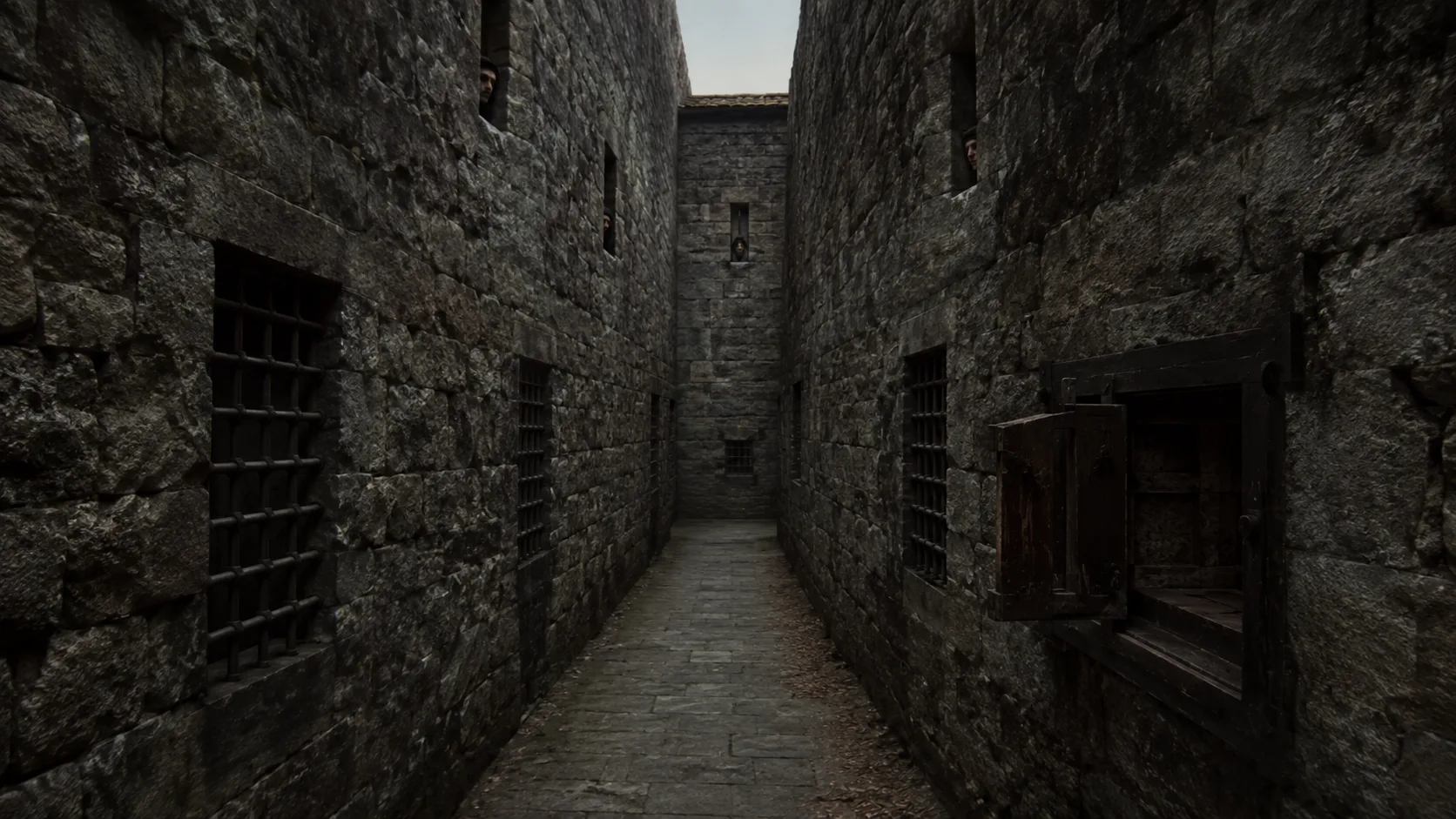 The bare lane between the two walls, watched from both sides, with iron grilles and a turning cupboard set into the stone.